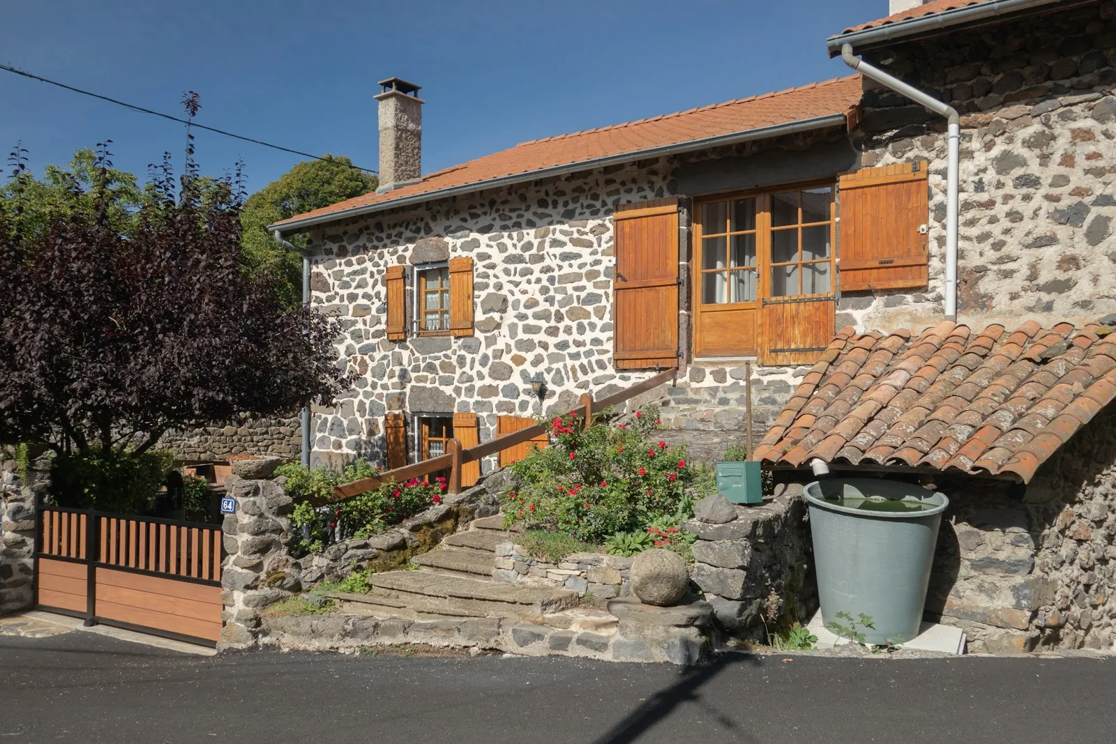Maison de pierre à volets en bois et toit de tuiles